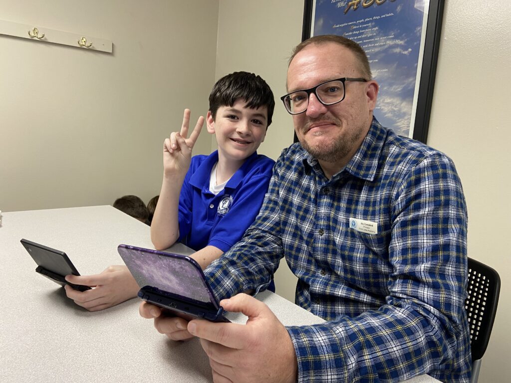 Great Lakes Academy student and the principal playing a video game in an after school club.